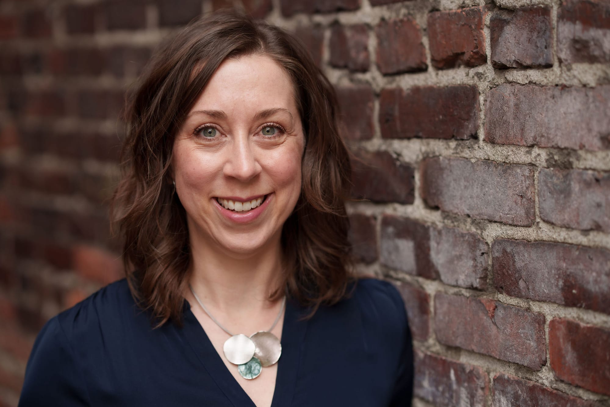 Rachel Wynn smiling, standing next to a brick wall