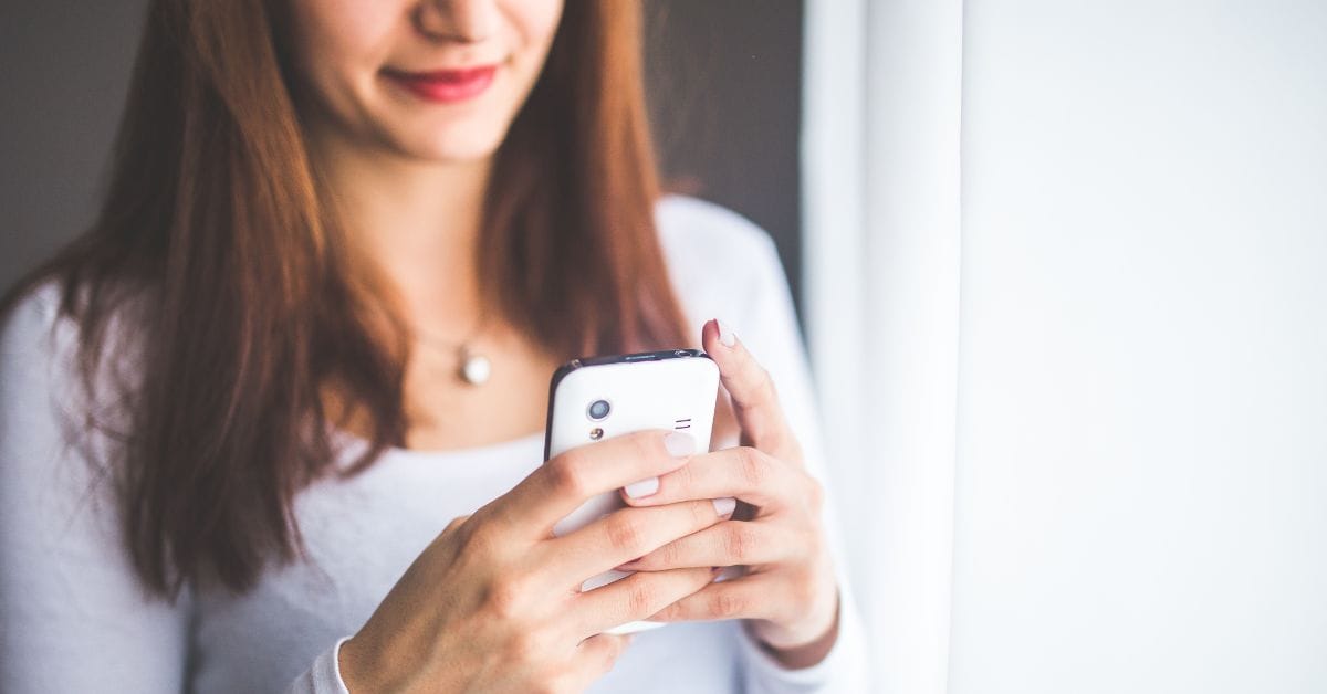 A woman holds a phone while looking at it.
