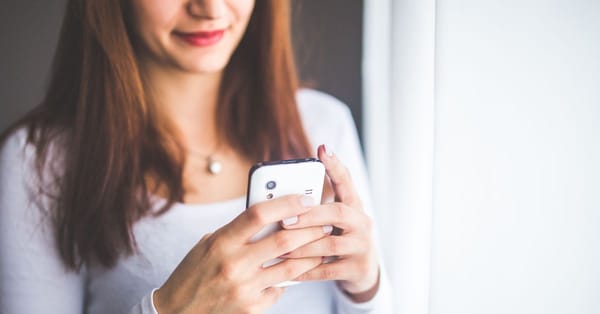 A woman holds a phone while looking at it.